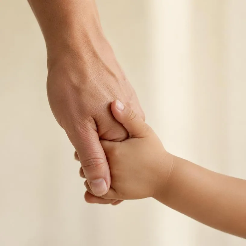 A small child's hand holding an adult's hand